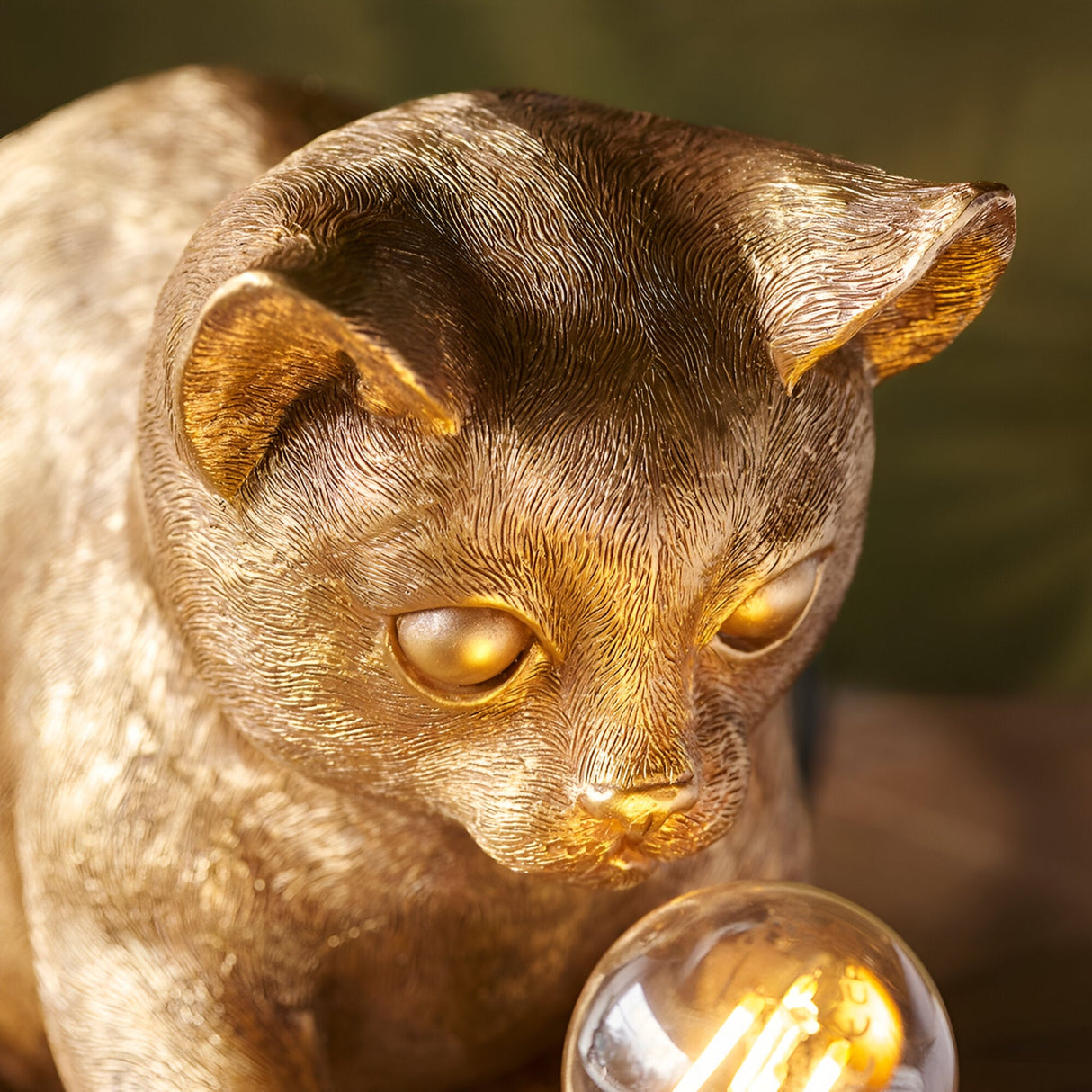 Close-up of the Endon Brockwick table lamp showing the vintage gold resin kitten's detailed face beside a warm filament bulb.