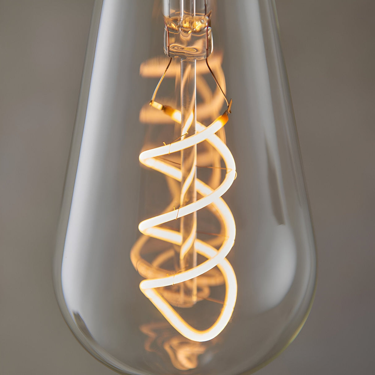 Close-up of Endon 4W E27 LED filament twist bulb showing the illuminated spiral filament within clear pear-shaped glass, glowing warm white.