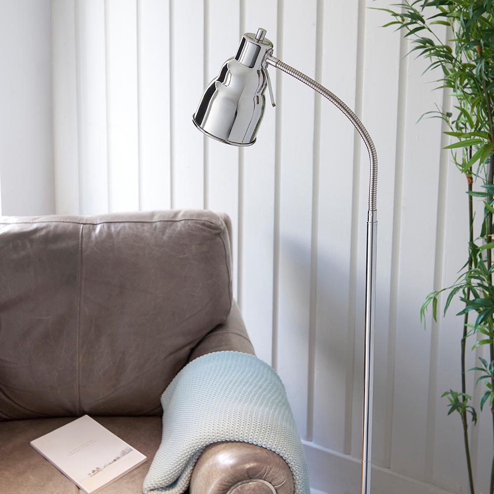 Endon Bevleigh nickel floor lamp with flexible gooseneck arm angled over a grey leather sofa with a pale knit throw and book, beside bamboo foliage.