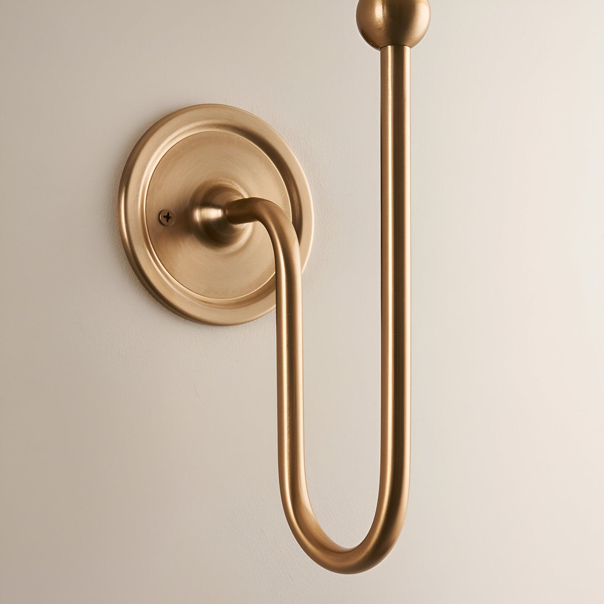 Endon Cliffleigh wall light fitting in brushed aged brass, with a slim upright arm, ball finial, curved hook and round flat back plate.