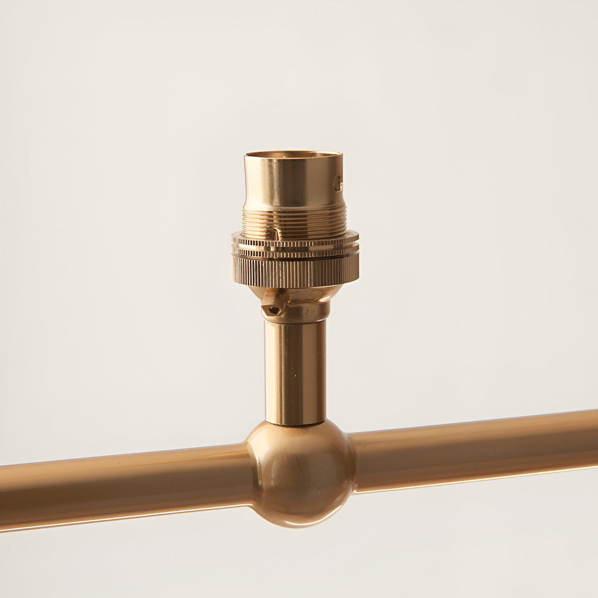 Close-up of an Endon Cliffleigh linear pendant detail in brushed aged brass, showing a B22 lamp holder above a decorative sphere on the bar.