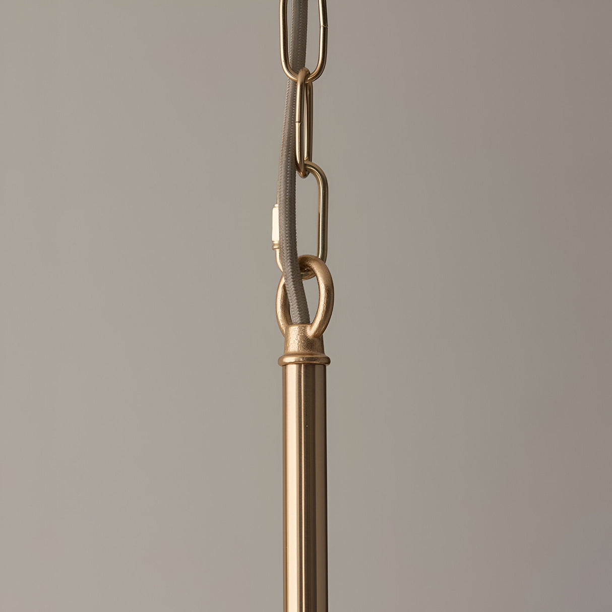Close-up of the Cliffleigh 5 Light Pendant's brass chain and grey braided fabric flex meeting the brushed brass rod, on a plain neutral background.