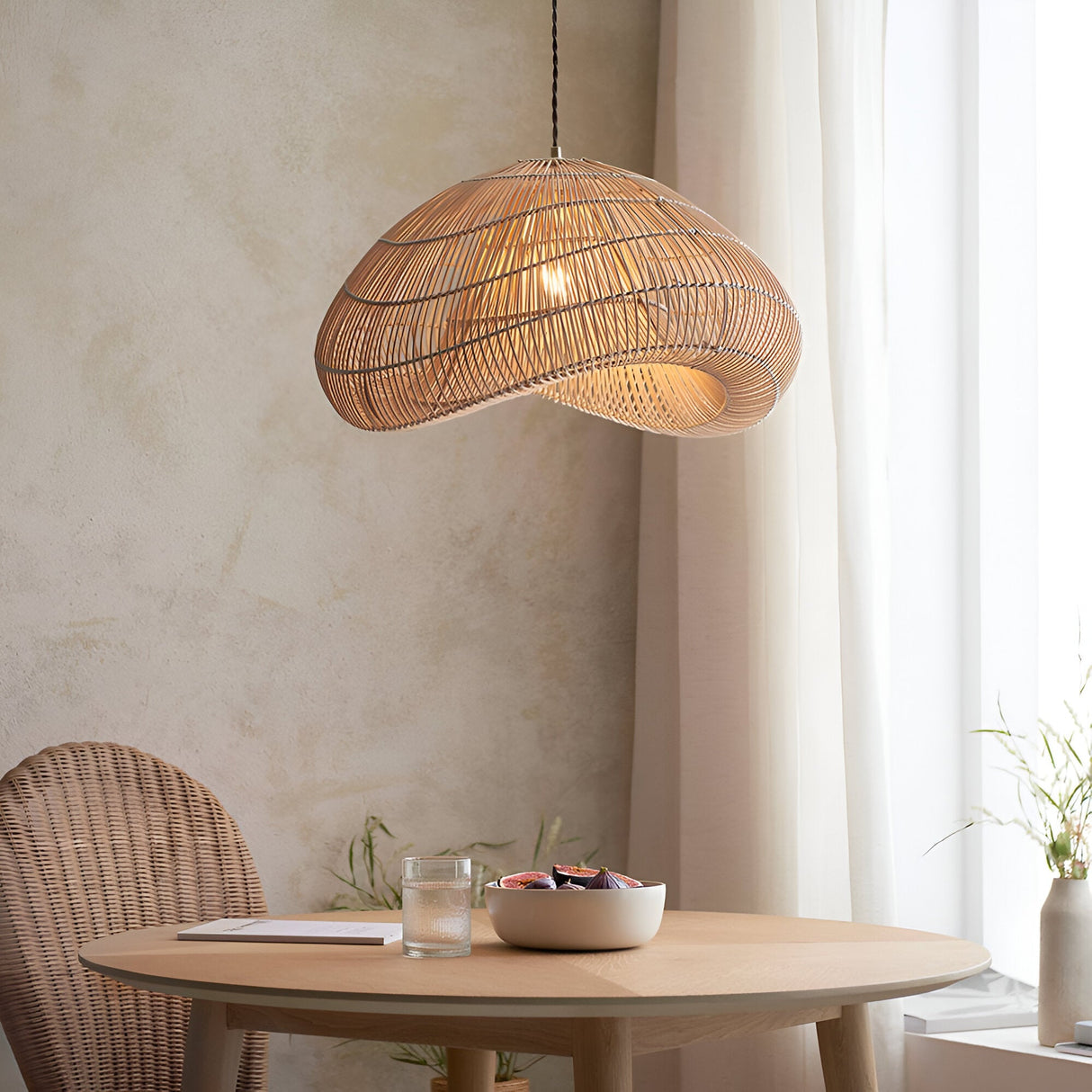 Endon Carlmere natural rattan pendant shade with hand-woven cloud shape, hung above a round wooden dining table in a sunlit neutral room.