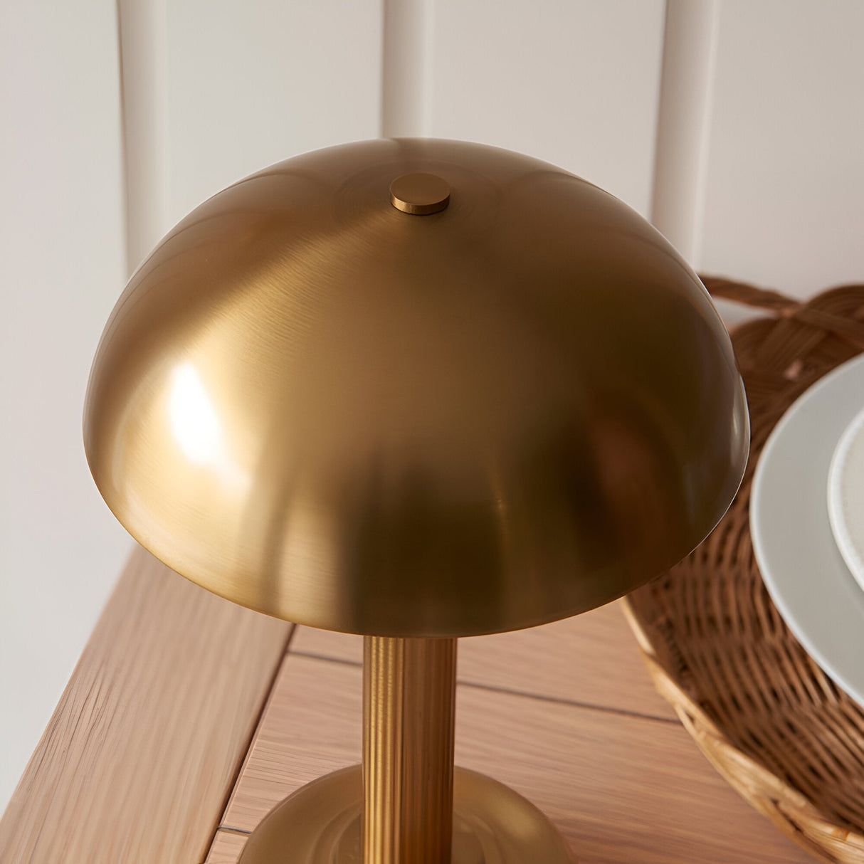 Endon Ashfield LED table lamp in brass with domed shade and touch dimmer button, shown on a wooden table beside a wicker basket.
