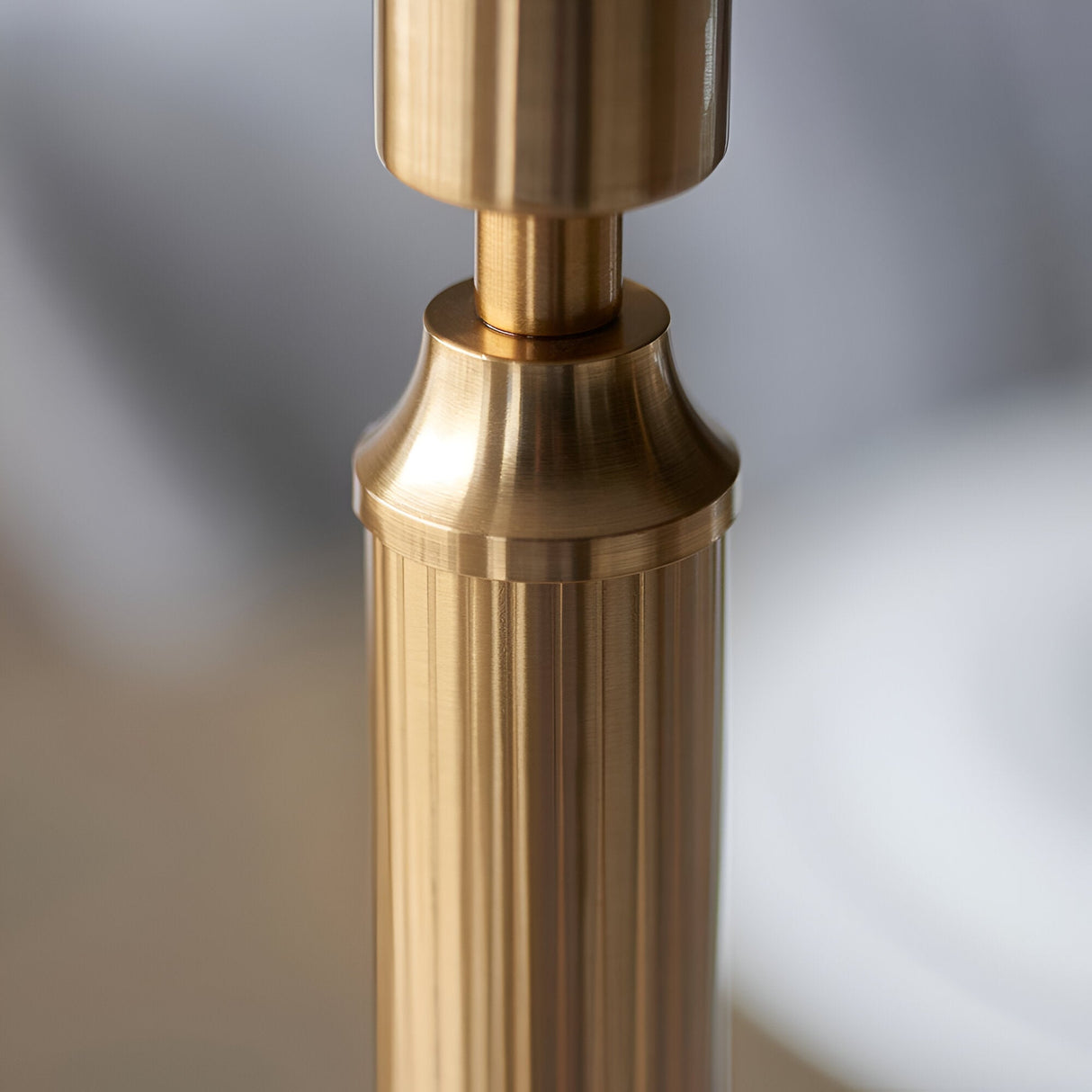 Close-up of the Endon Cranwick LED table lamp's brushed aged brass stem, showing the reeded column and tailored collar detail.
