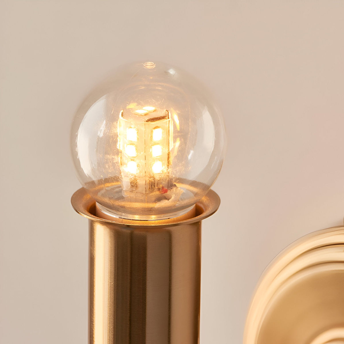 Close-up of the Endon Ashstead LED rechargeable wall light showing its clear globe bulb and brushed aged brass cylindrical holder.