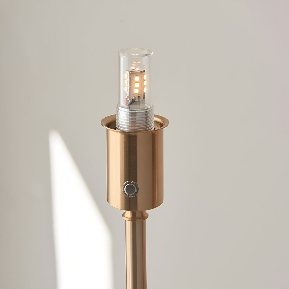 Close-up of the Endon Ashstead LED rechargeable floor lamp's aged brass holder with integrated LED bulb and touch dimmer button.