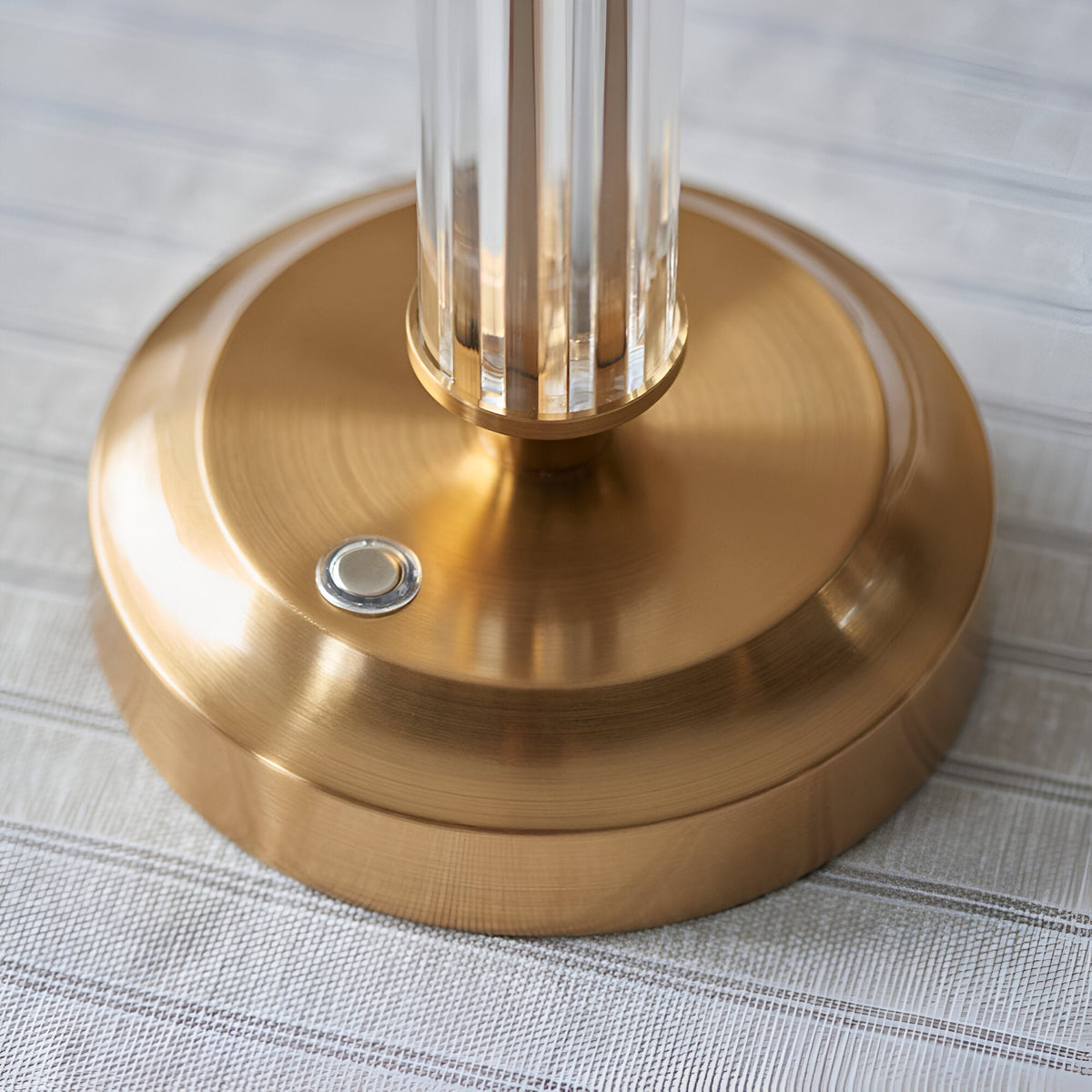 Close-up of the Endon Carlwood LED table lamp base in brushed aged brass with clear acrylic column detail and a touch dimmer button.