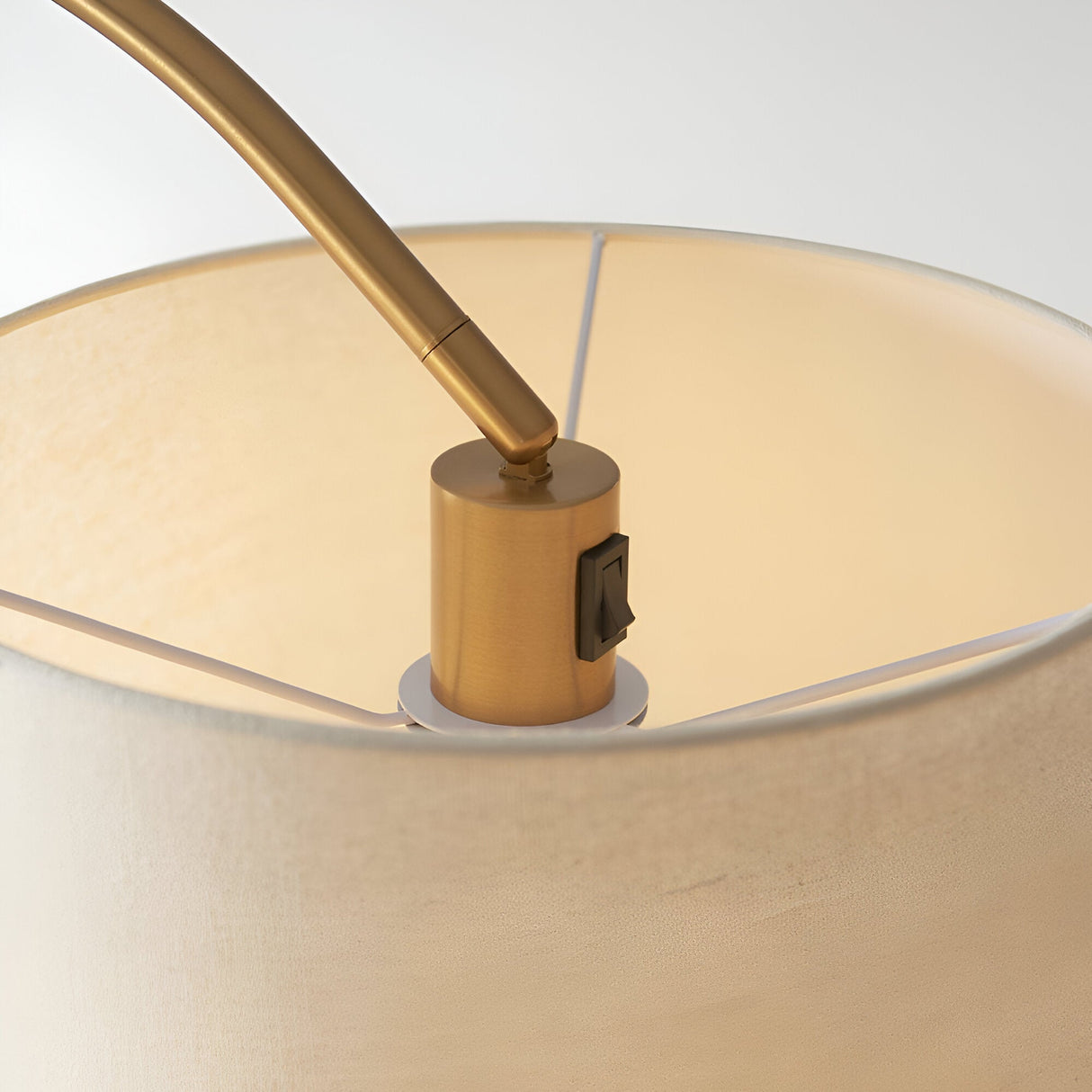 Close-up of Endon Bevbourne floor lamp showing brass lamp holder with black switch, tilting arm, and natural fabric shade interior.