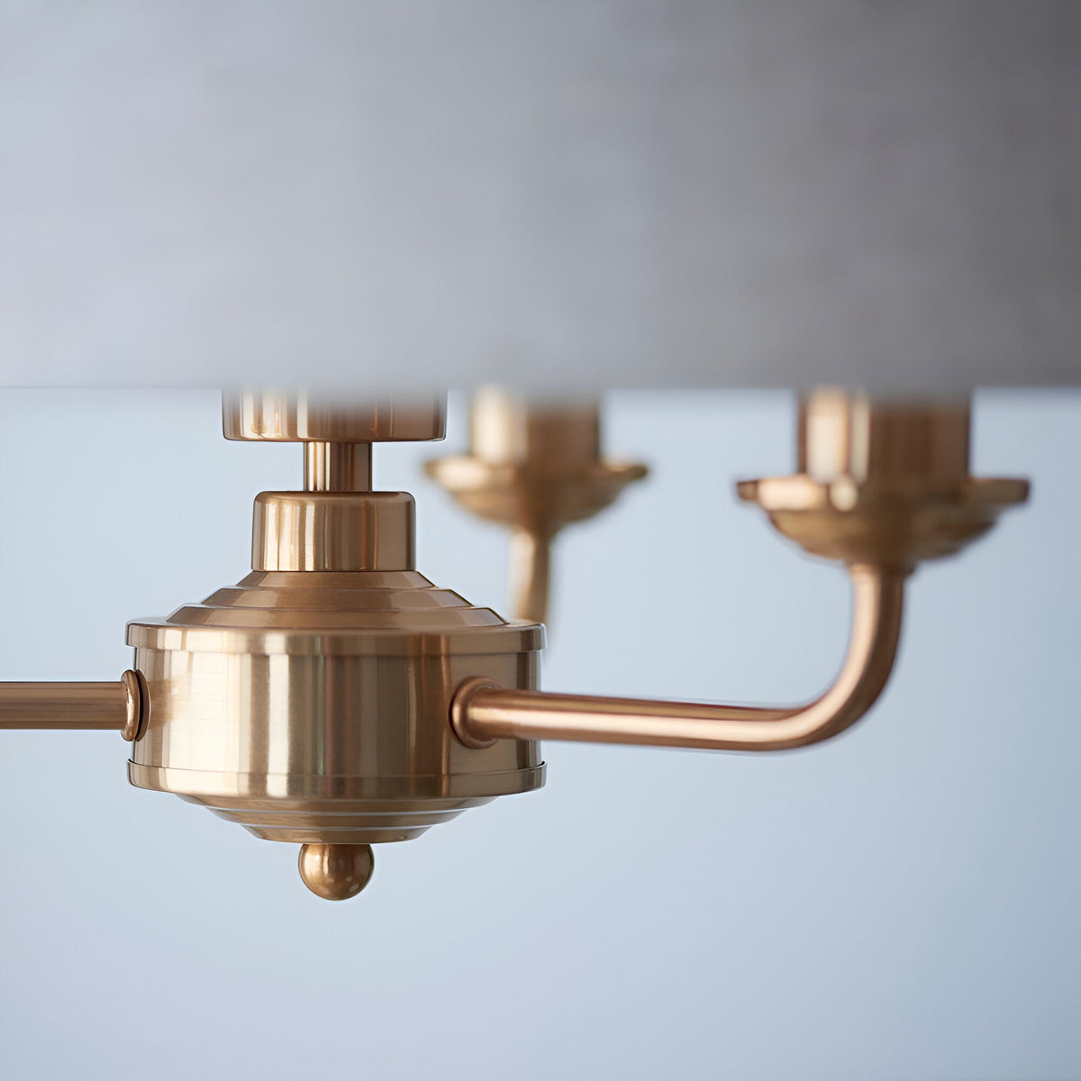 Close-up of the Brenley 3 Light Pendant in vintage brass, showing E14 lamp holders and curved arms beneath a fabric shade, against a plain grey background.