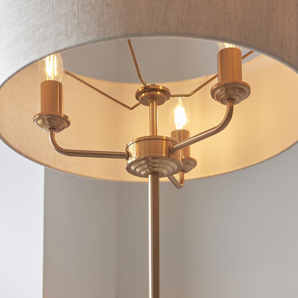 Close-up of the Endon Brenley 3 Light Floor Lamp in brass, showing three E14 candle bulbs on curved arms beneath a wide natural linen shade.