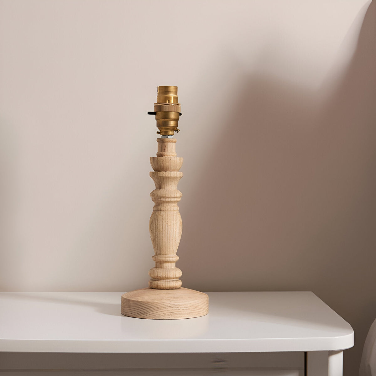 Endon Aldworth turned wood spindle table lamp in natural ash with brass B22 switched lampholder, shown shadeless on a white side table.