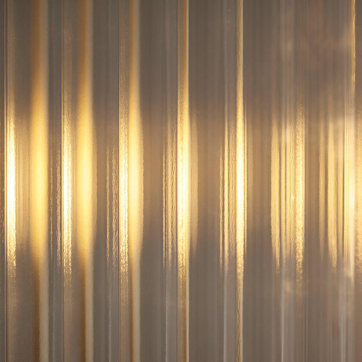 Rothbury 4 Light Linear Pendant in antique brass, close-up of ribbed glass panel shades glowing warmly along the bar fitting.