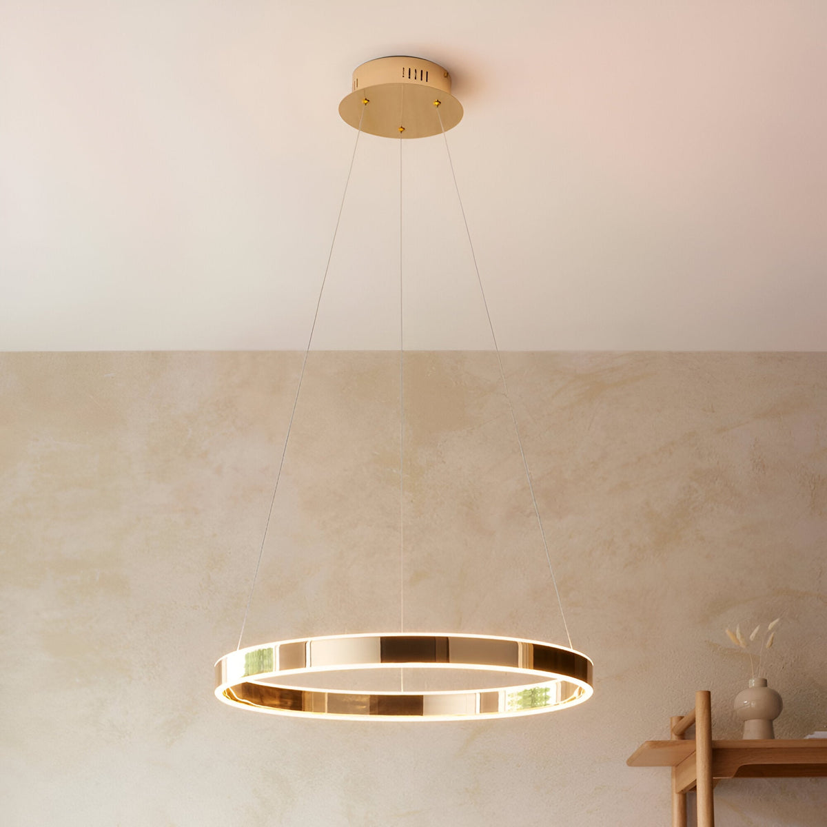 Endon Bramford LED pendant in French gold with a slim horizontal ring and frosted diffuser, suspended on wire cables above a neutral plaster wall.
