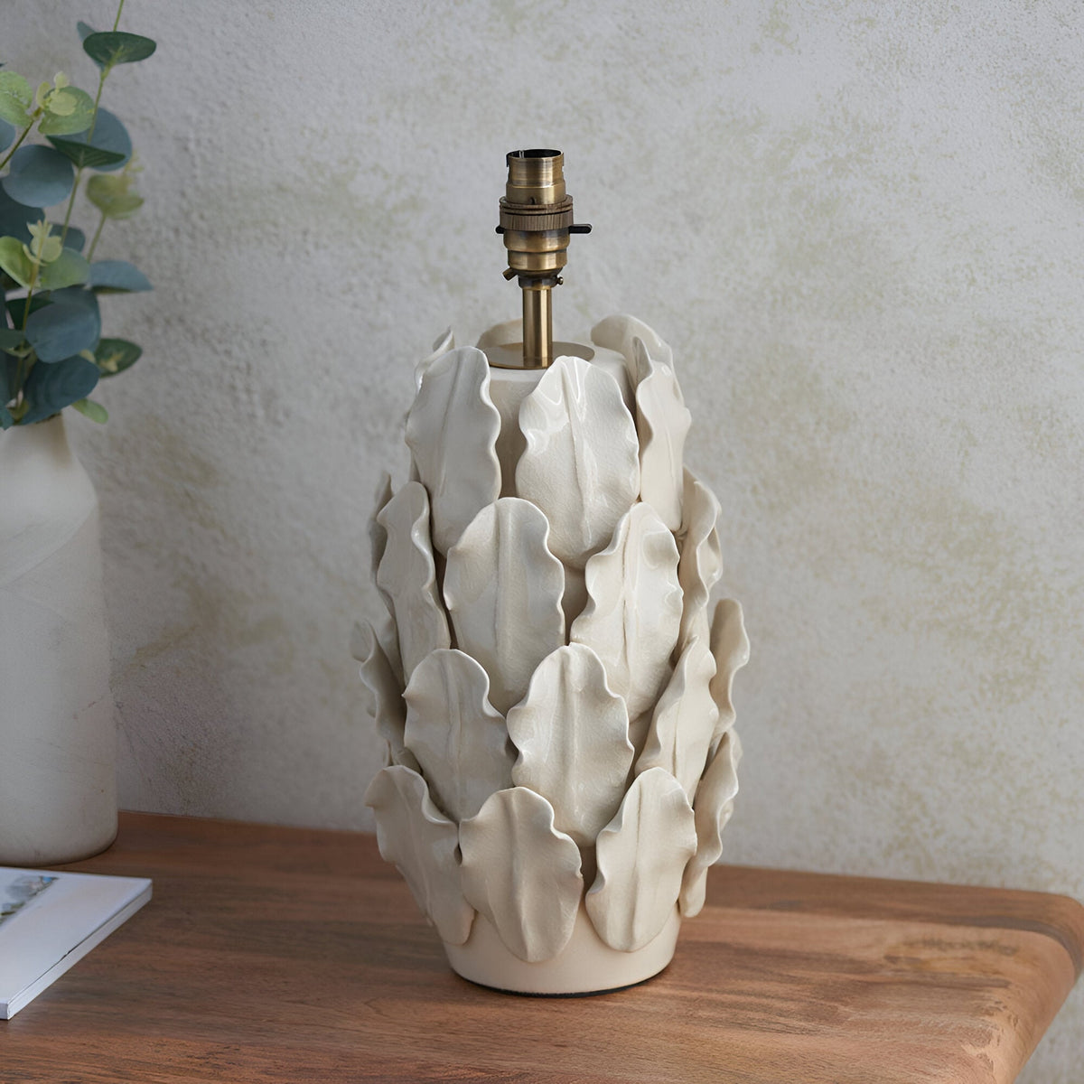Endon Caldford large ceramic table lamp base in cream with ivory crackle glaze, handmade leaf detailing and aged brass B22 holder, on a wooden side table.