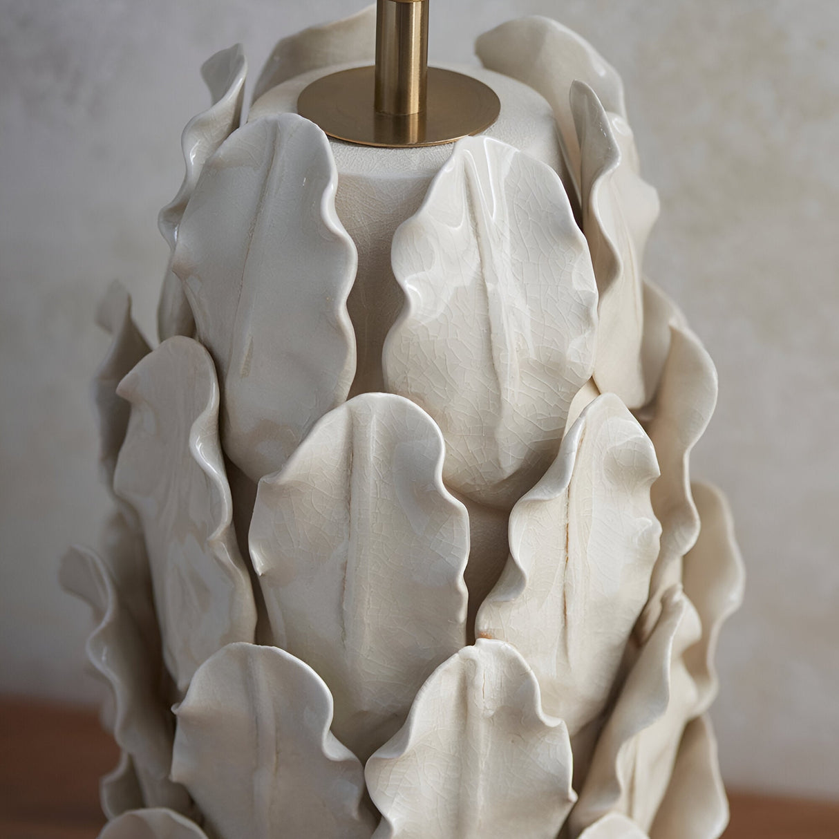 Close-up of the Endon Caldford Large Table Lamp base in cream, showing ivory crackle-glazed ceramic leaf detailing around an aged brass B22 lamp holder.
