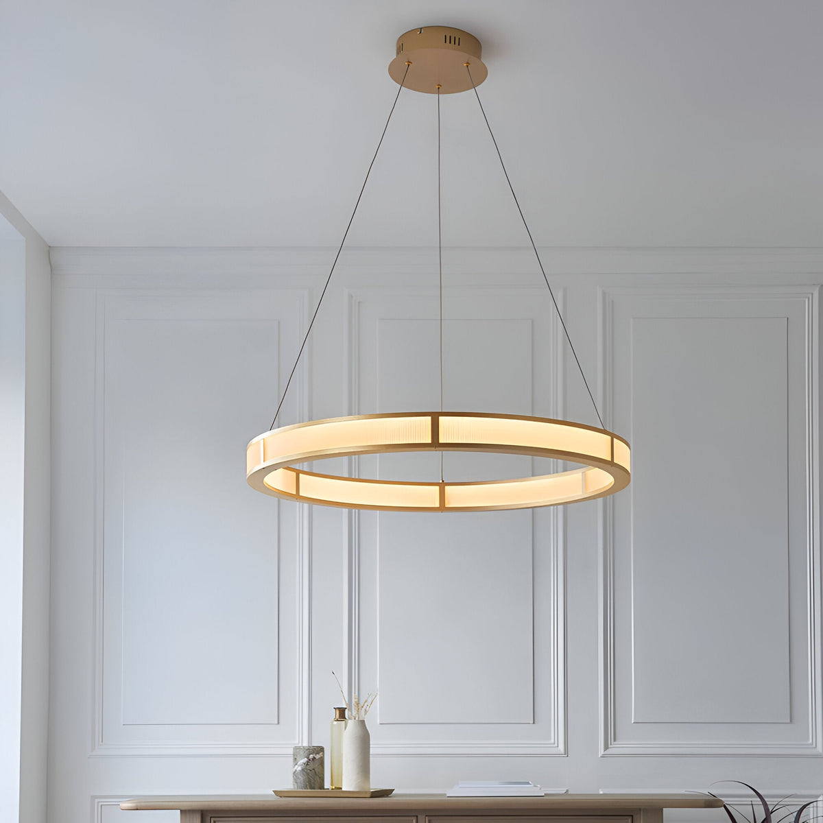 Endon Bevley brushed gold LED ring pendant with ribbed frosted acrylic diffuser, suspended from clear cables above a console in a panelled room.