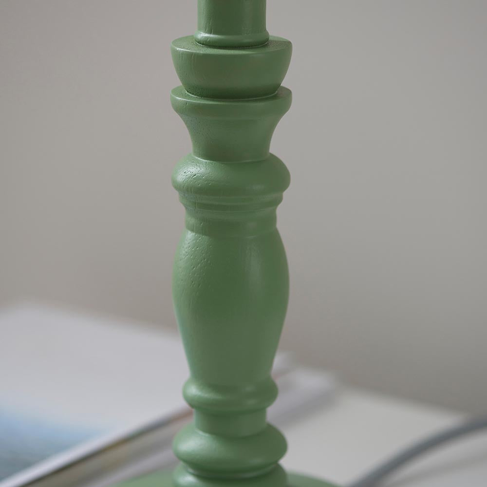 Close-up of the Aldworth Table Lamp's turned wooden spindle base in a matte green finish, shown against a neutral indoor background.