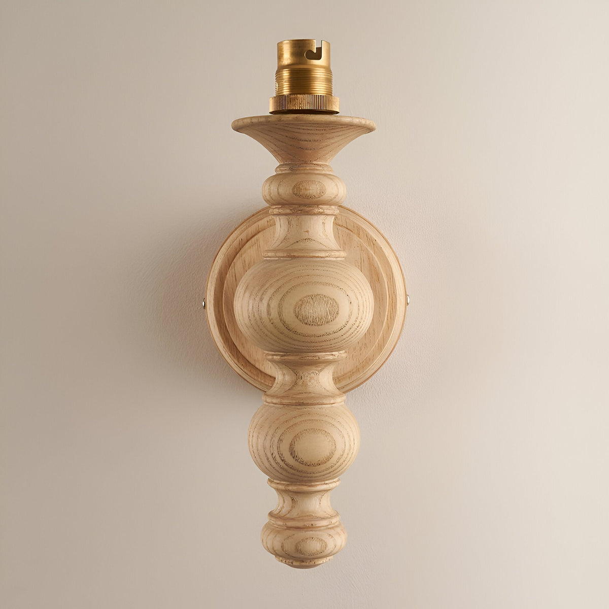 Endon Aldworth wall light in natural ash with turned spindle body and brass B22 lampholder, shown shadeless against a plain neutral wall.