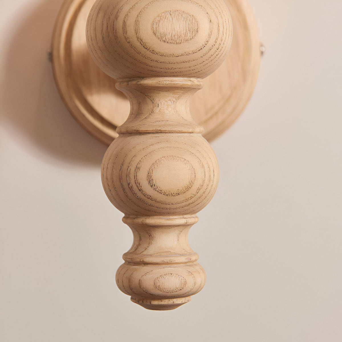 Close-up of the Endon Aldworth wall light showing the turned natural ash spindle with visible grain and circular wall plate.