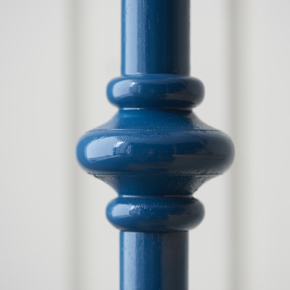 Close-up of the turned wooden spindle detail on the Endon Bevbury Floor Lamp in satin marlin blue, showing the rounded central bobbin against a pale background.