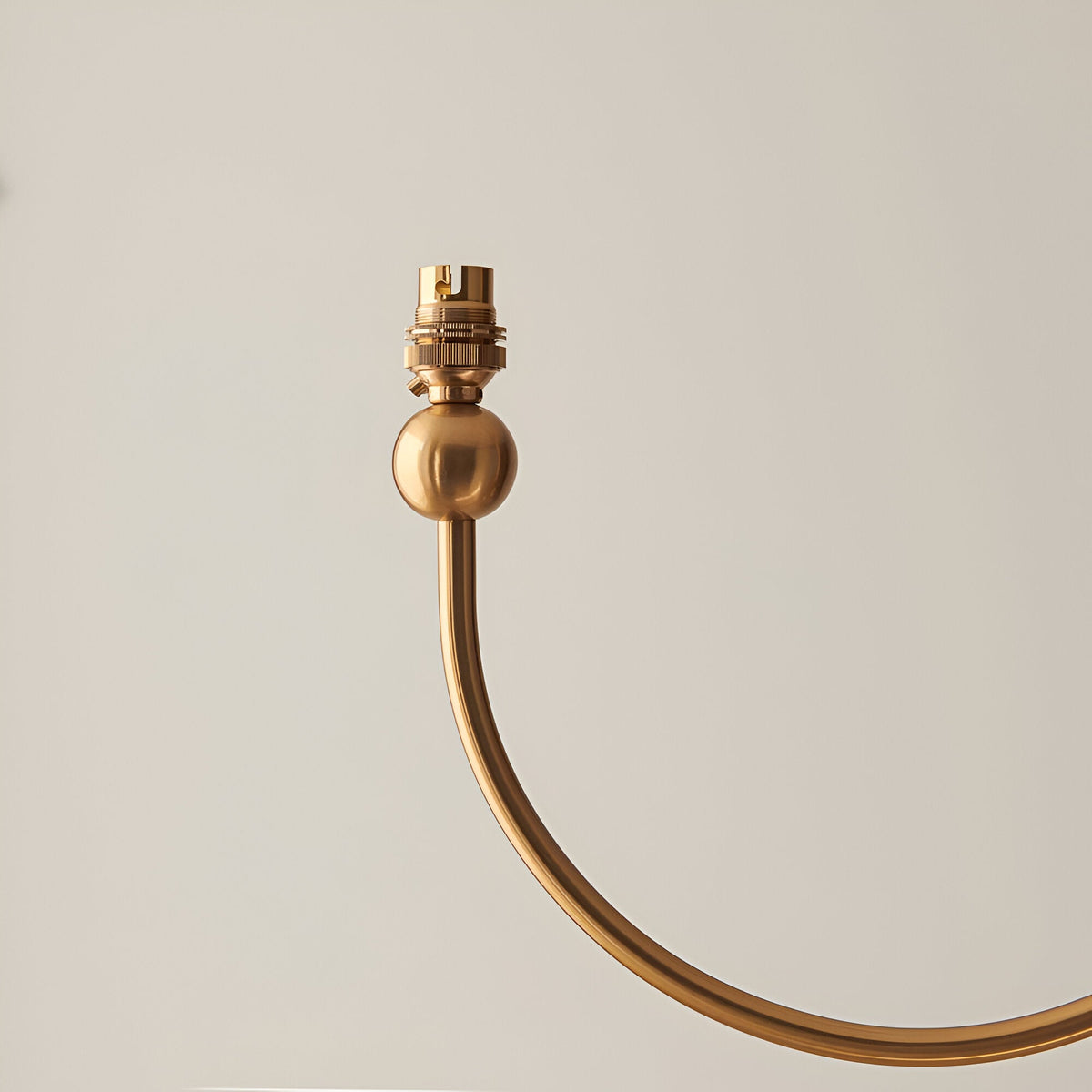 Close-up of one curved J-shaped arm on the Endon Cliffleigh chandelier in brushed aged brass, showing the B22 lamp holder and ball detail.