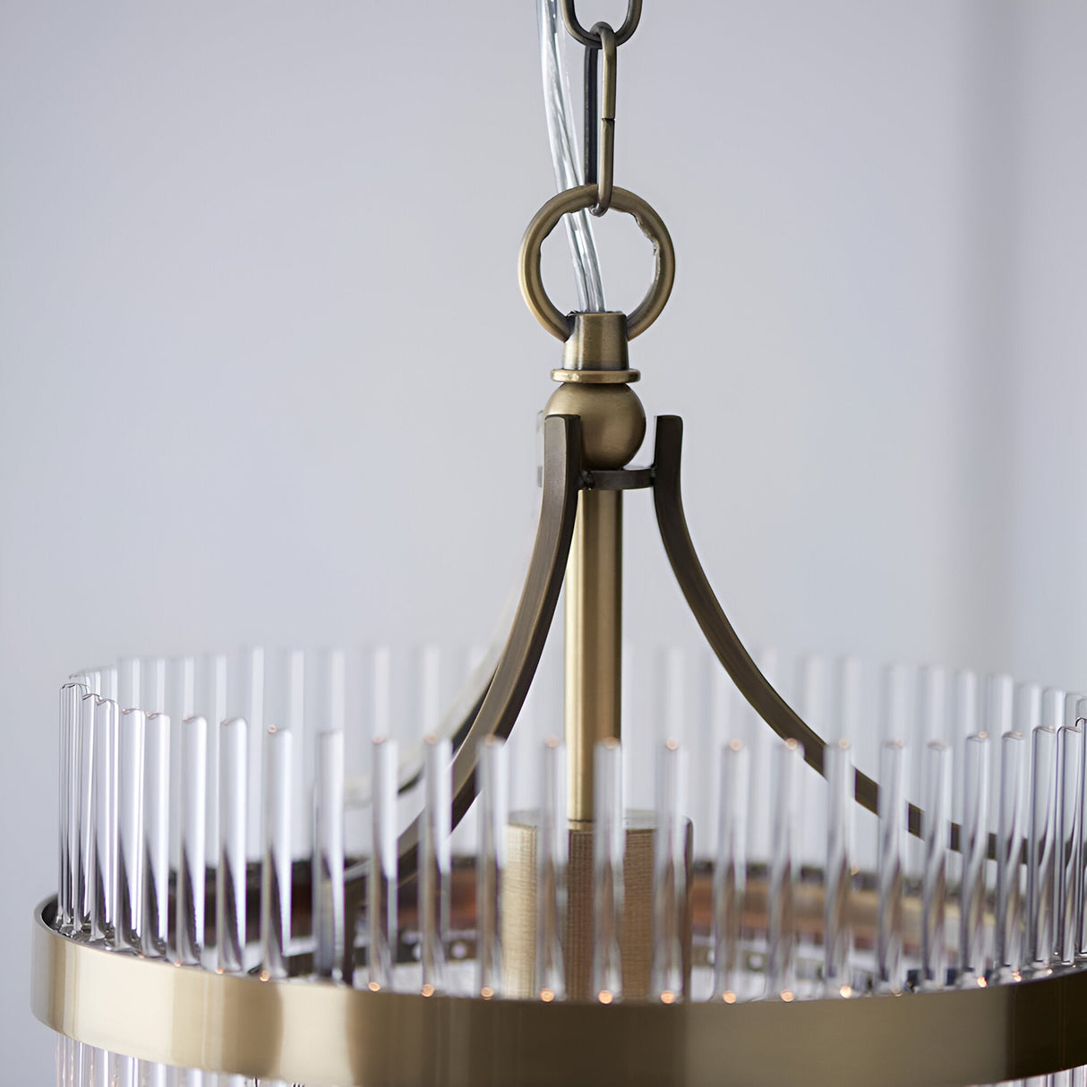 Close-up of Endon Beaumont pendant showing antique brass chain suspension, curved arms, and clear glass rods around the compact circular frame.