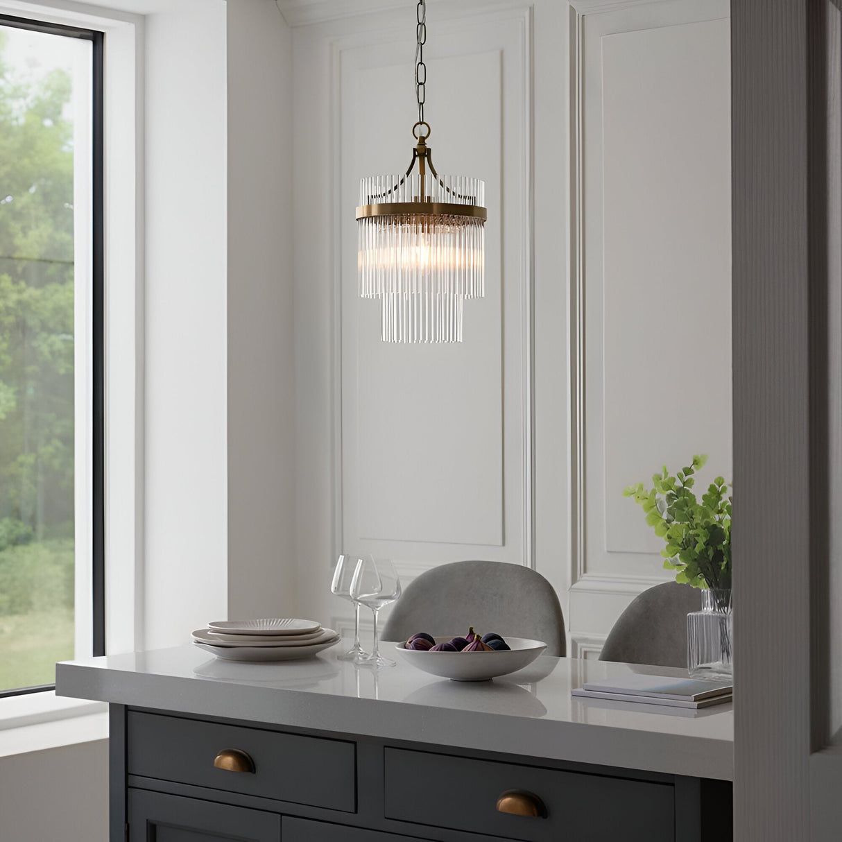 Endon Beaumont pendant in antique brass with tiered clear glass rods, hung above a grey kitchen island with dinnerware in a bright dining space.