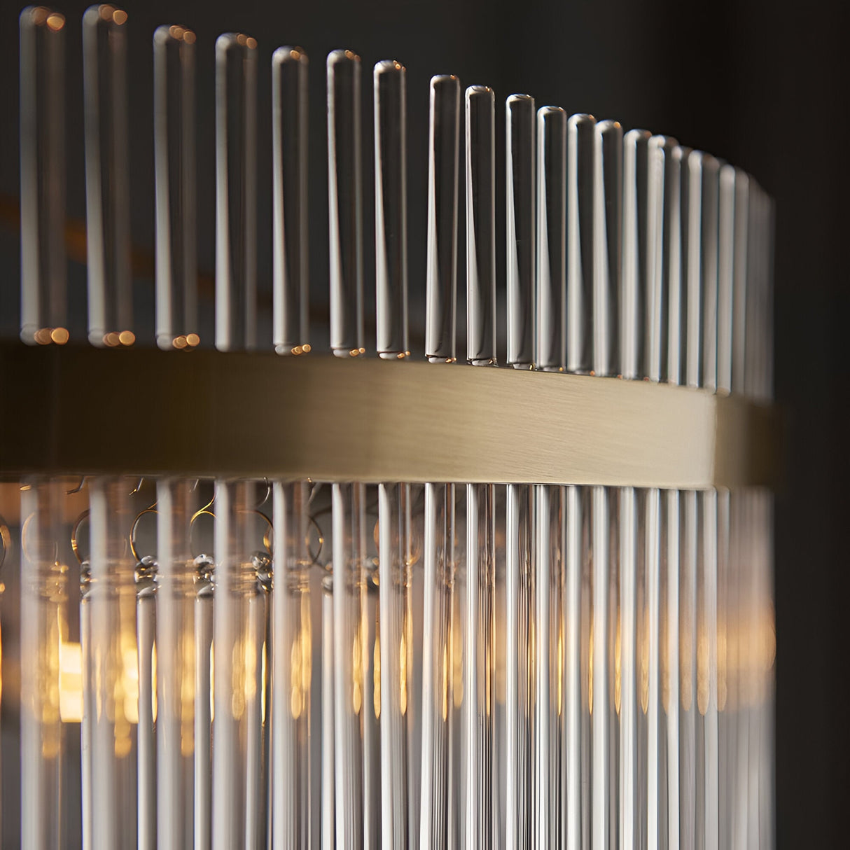 Close-up of the Endon Beaumont 7 Light Pendant showing antique brass banding and clear glass rods diffusing warm light.