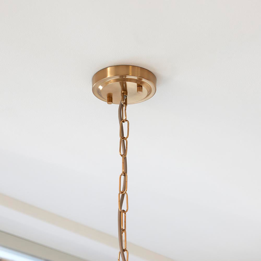 Close-up of the Endon Brenbury pendant ceiling rose in brushed brass with a twisted grey fabric cable feeding into a linked brass chain.