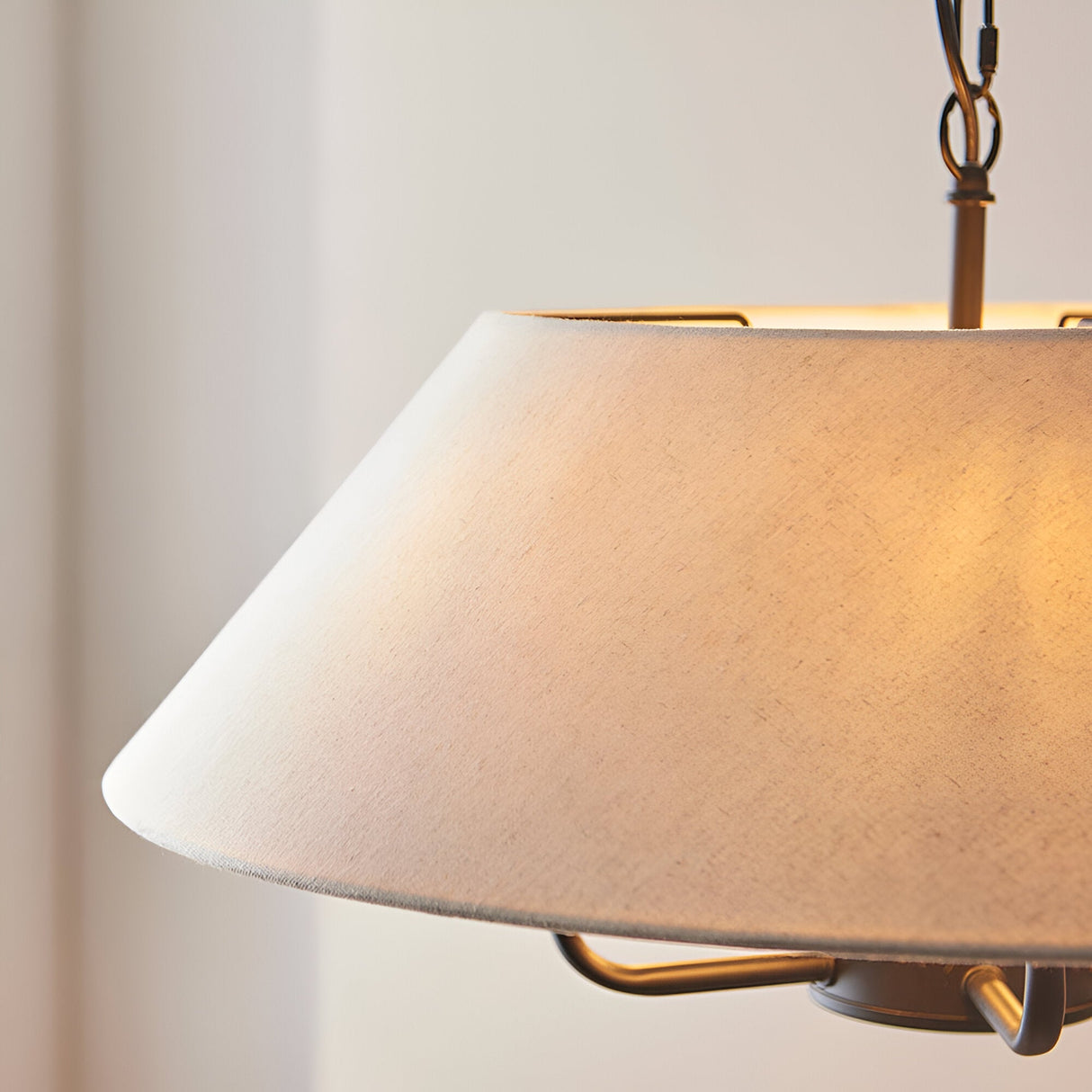 Endon Caldmere 5 Light Pendant close-up with tapered natural linen shade warmly lit, black metalwork and chain suspension against a pale wall.