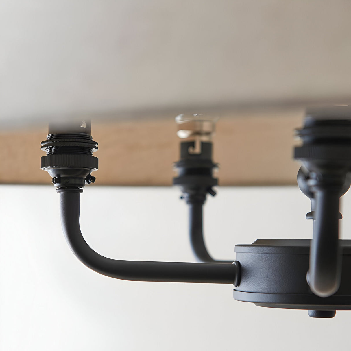 Close-up of Endon Caldmere 5 Light Pendant in black, showing two matt black curved arms with B22 lamp holders extending from a round ceiling plate.