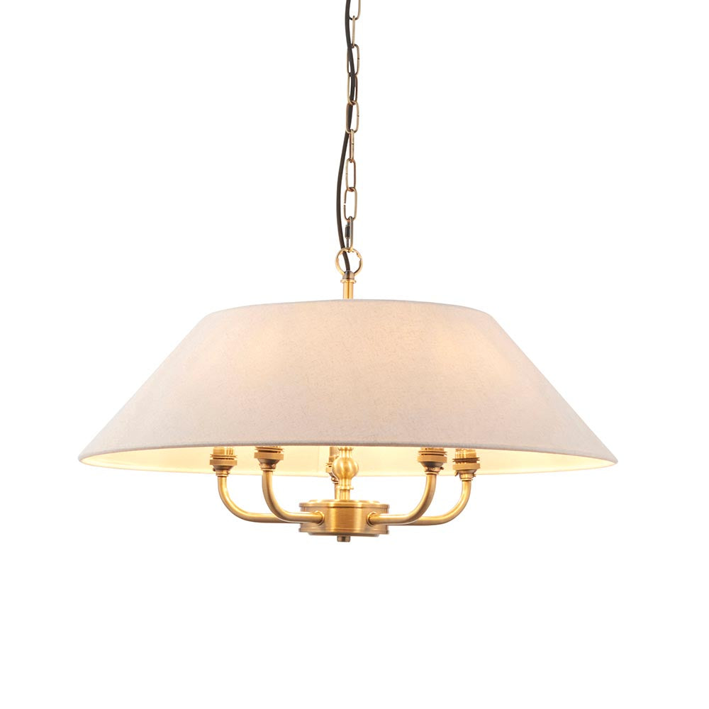 Caldmere 5 Light Pendant in brass, with a wide natural fabric drum shade and five arms, hung from a chain and black cable on a plain white background.