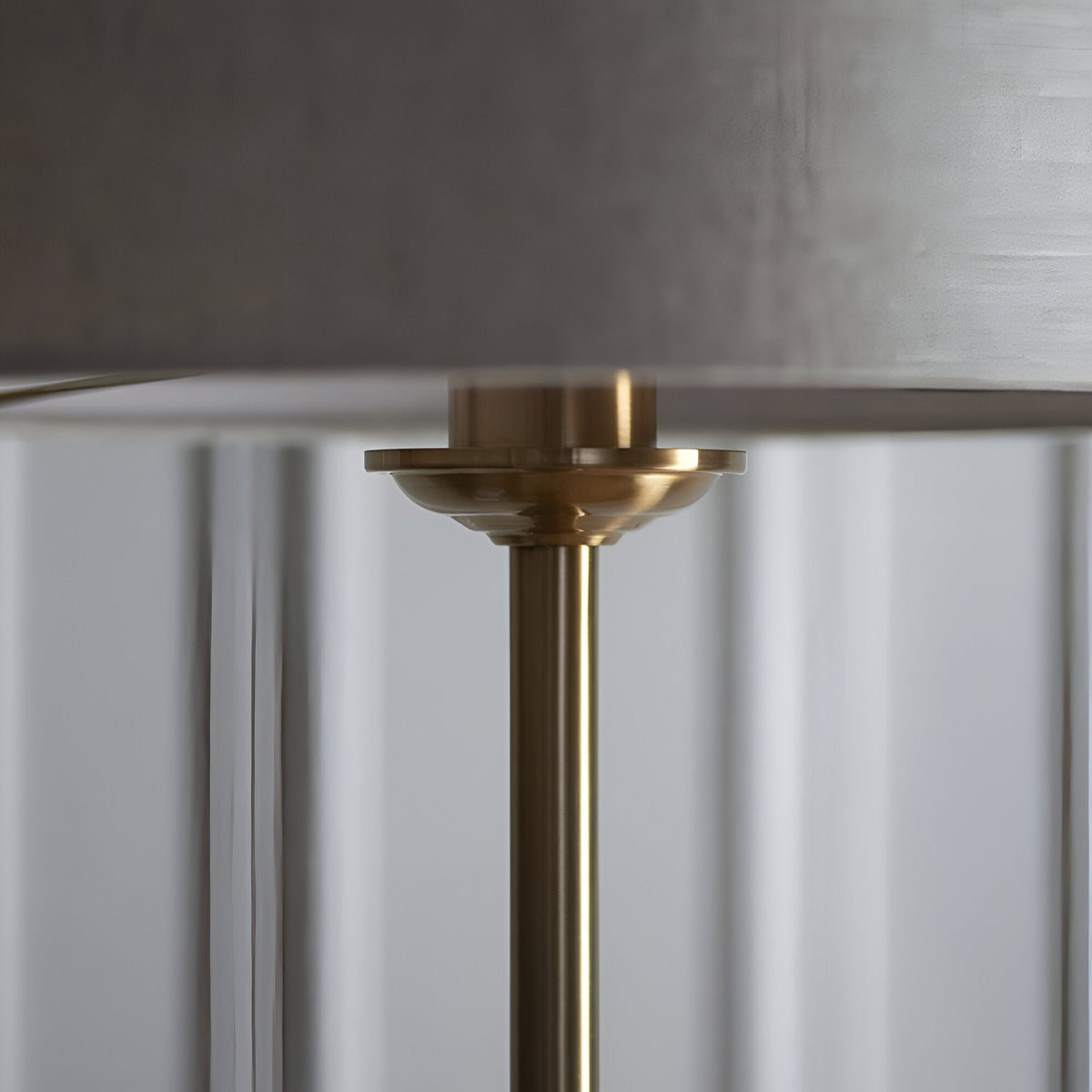 Close-up of the Brenley Floor Lamp in brass, showing the brushed metal stem and finial beneath a fabric shade with reflective inner lining.