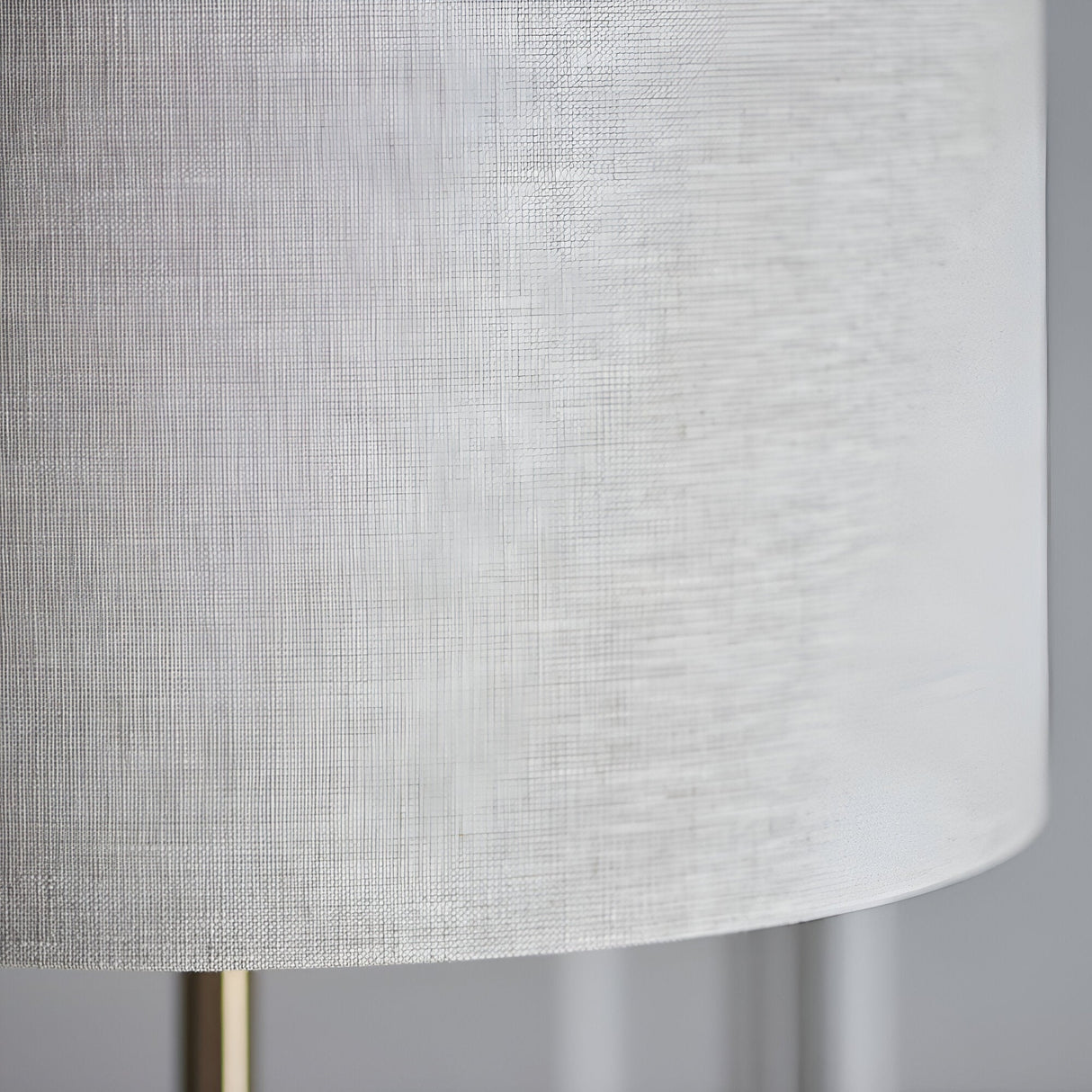 Close-up of the Brenley Floor Lamp in brass, showing the textured white fabric drum shade and slim brass leg on a plain background.