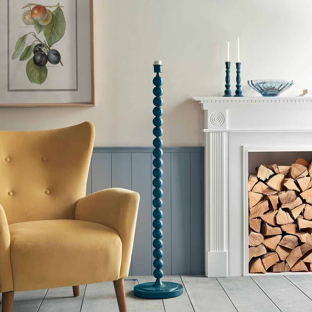 Endon Brenleigh floor lamp base in glossy marlin blue with stacked metal spheres and round base, shown beside a yellow armchair and white fireplace.