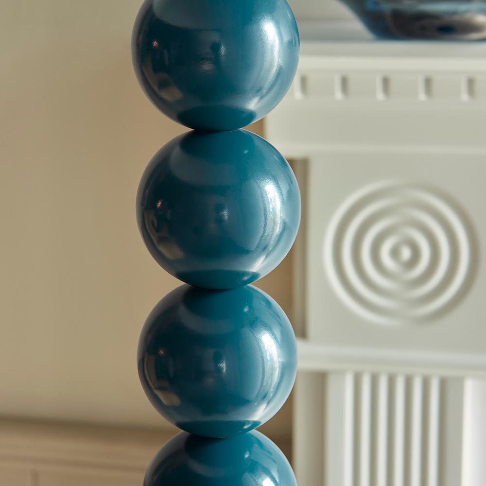 Close-up of the Endon Brenleigh Floor Lamp base showing stacked glossy marlin blue metal spheres beside a white fluted cabinet.