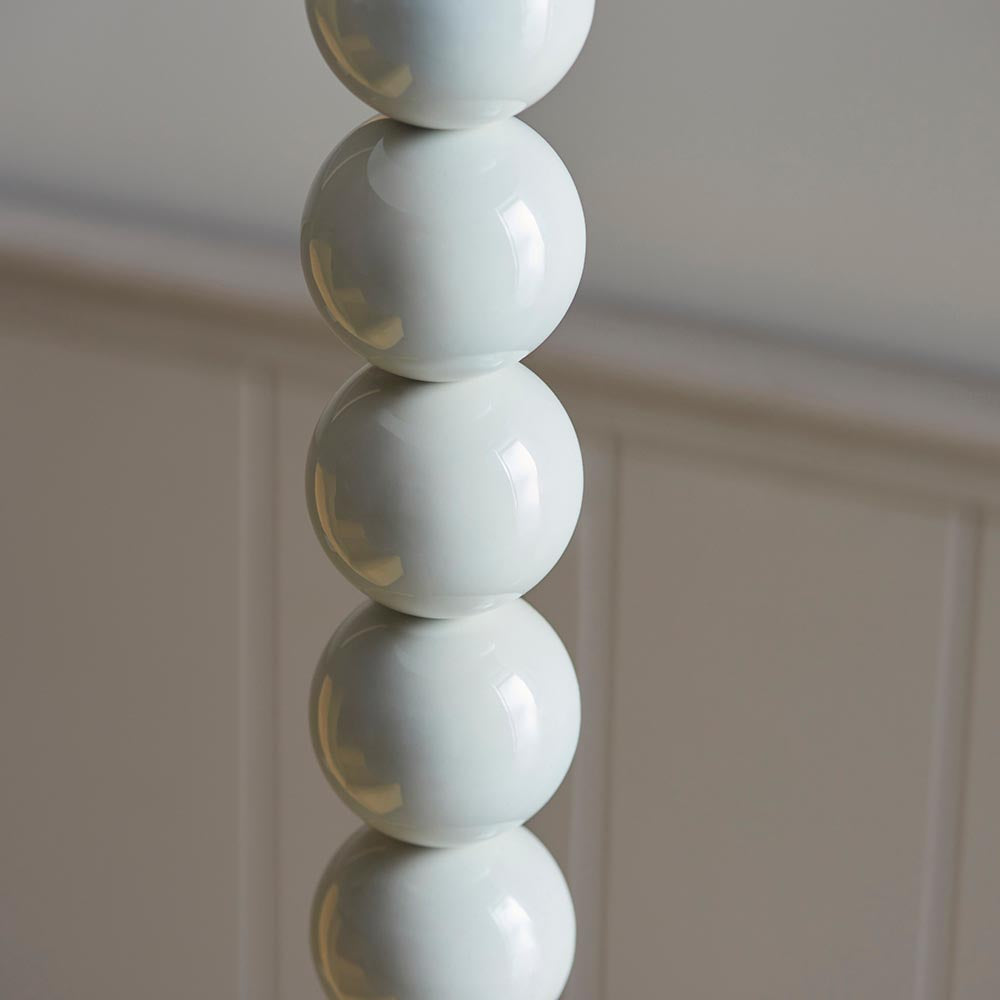 Close-up of the Endon Brenleigh Floor Lamp base in white, showing stacked glossy metal spheres against a pale panelled wall.