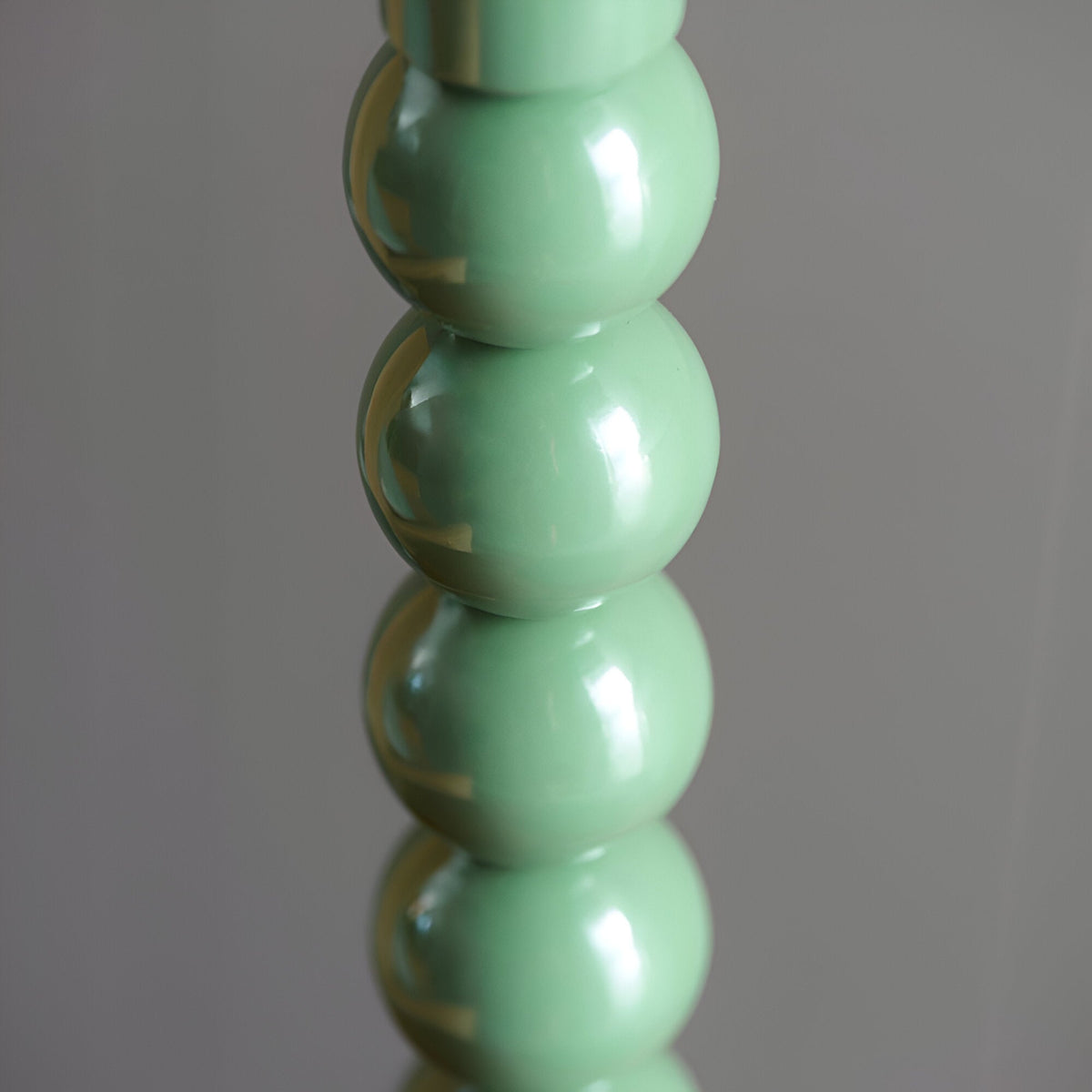 Close-up of the Endon Brenleigh table lamp base showing stacked glossy green metal spheres against a soft grey background.