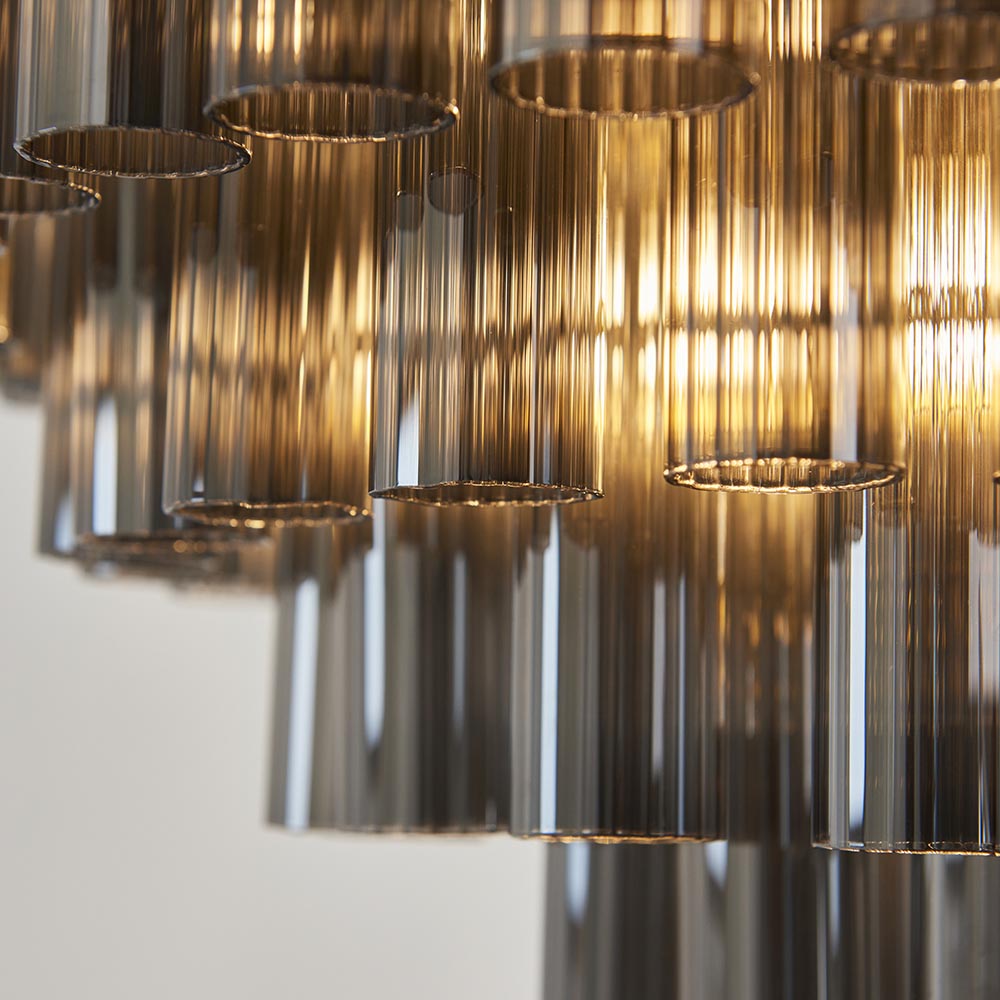 Close-up of Endon Cranshaw 12 Light Tiered Pendant showing smokey grey ribbed glass cylinders suspended from a satin brass frame.