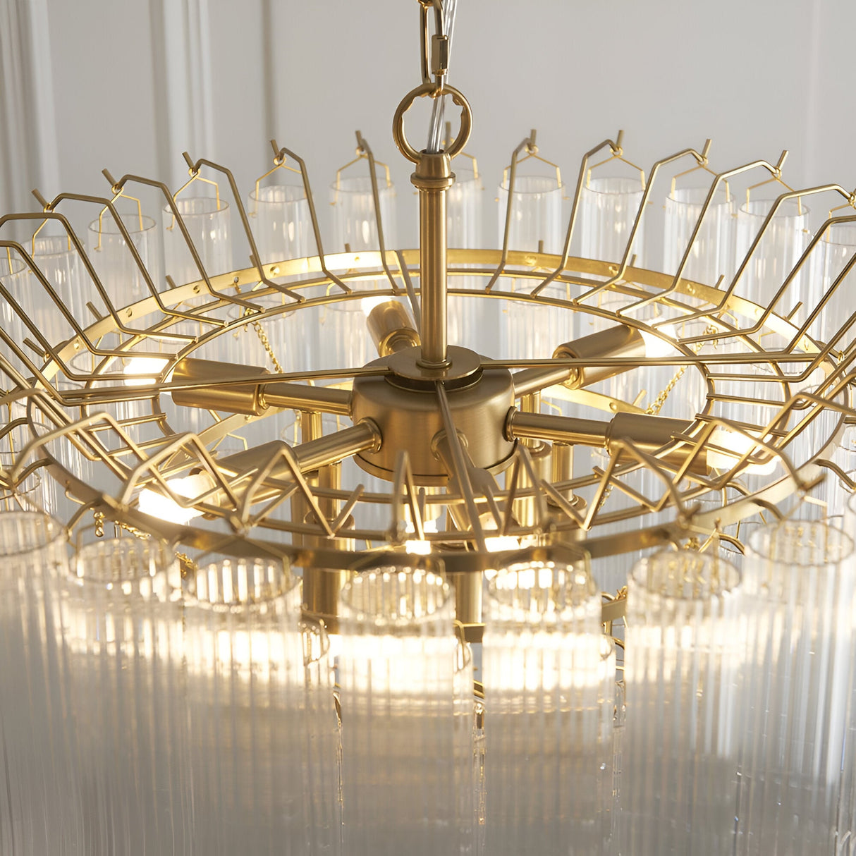 Close-up of Endon Cranshaw 12 light tiered pendant showing satin brass frame, central rod, chain suspension and ribbed clear glass cylinders.