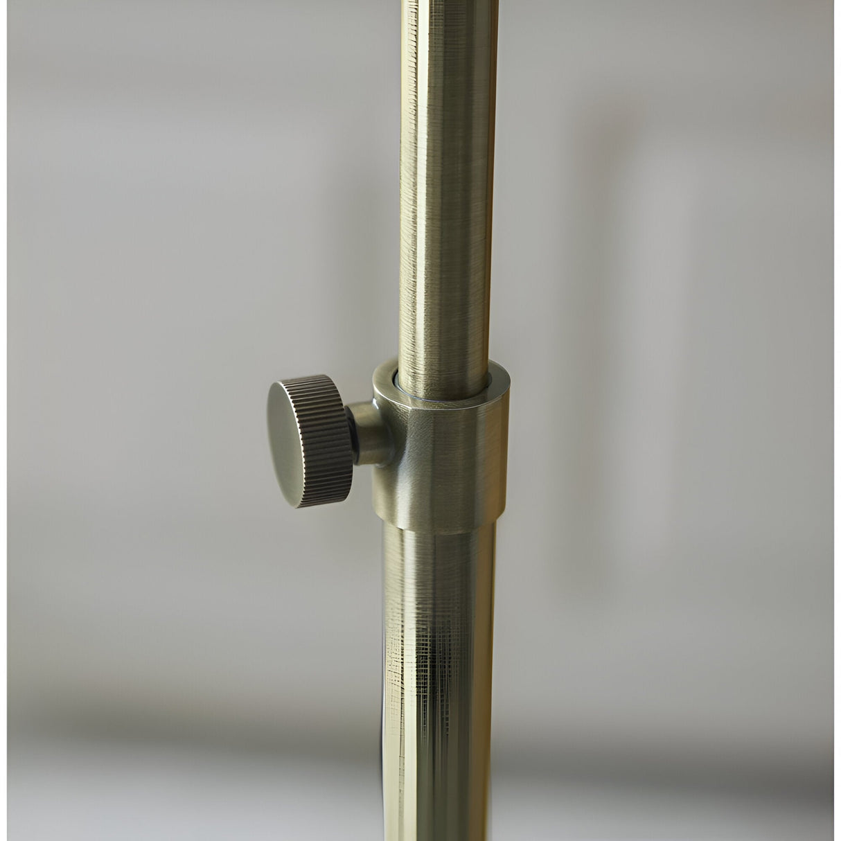 Close-up of the Endon Chartbourne floor lamp's antique brass stem with a knurled height-adjustment knob on the telescopic pole.