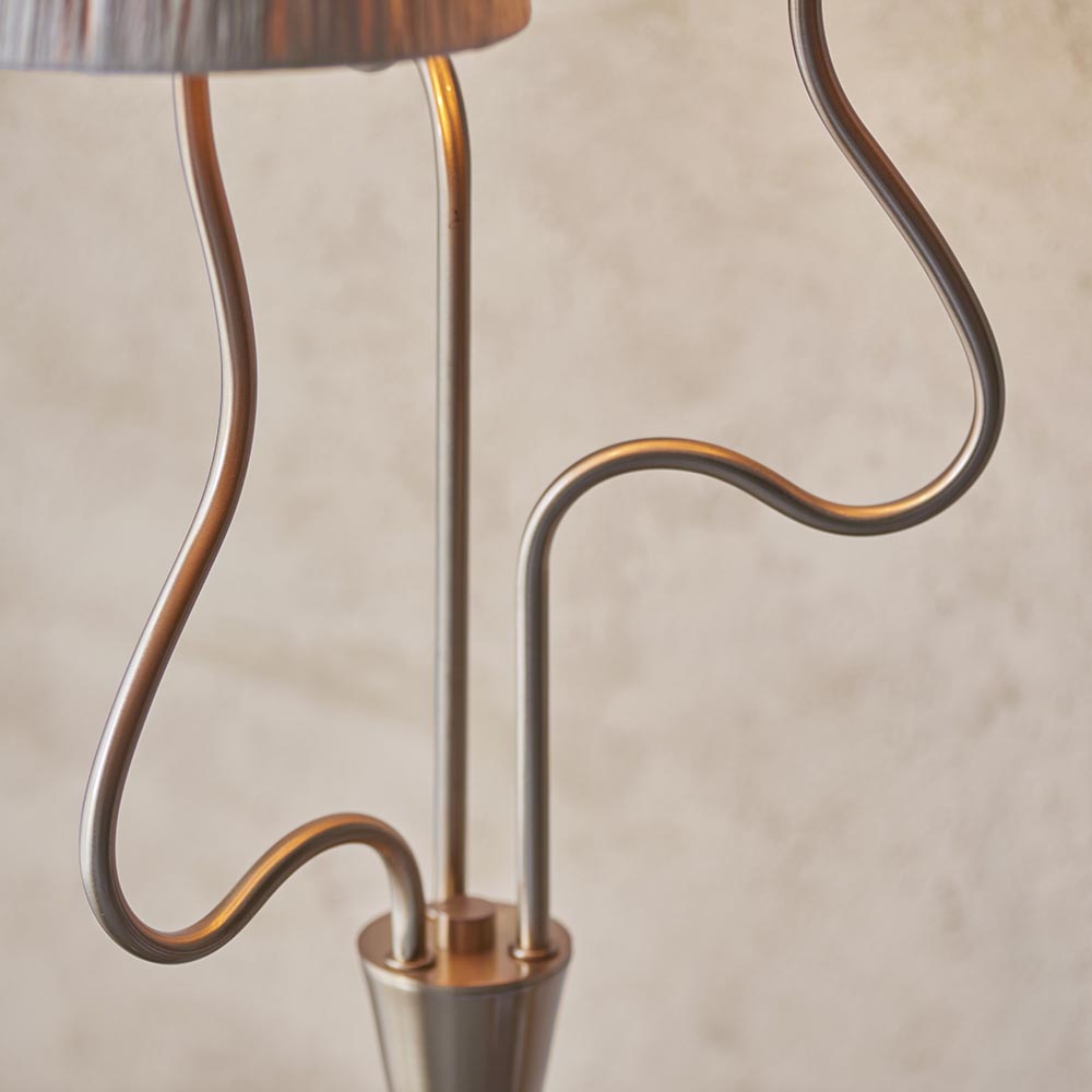 Close-up of the Danemont 3 Light Floor Lamp's wriggle stem in brushed aged brass, showing three curved metal arms meeting at a tapered base.