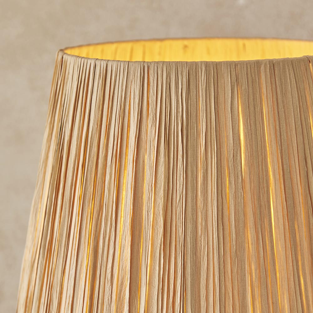 Close-up of the Endon Danemont floor lamp's tapered raffia shade in natural woven finish, glowing warmly against a neutral backdrop.
