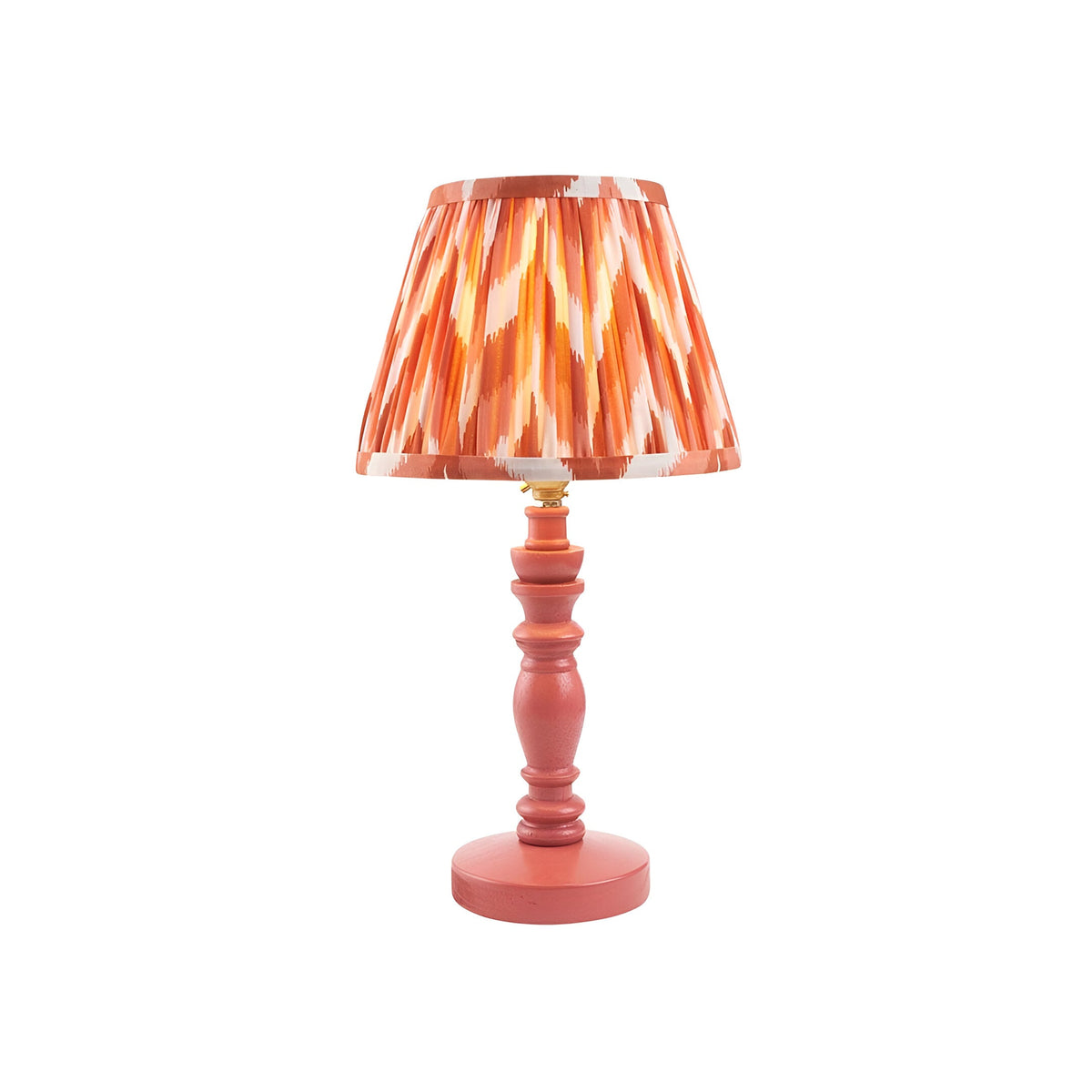 Aldworth Zigzag table lamp with a pink wooden spindle base and pleated orange zigzag-print fabric shade, brass B22 lamp holder, on a plain white background.