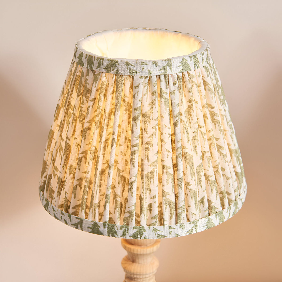 Aldworth Leaf table lamp with turned natural ash spindle base and pleated cream fabric shade featuring a green leaf print, shown against a plain background.