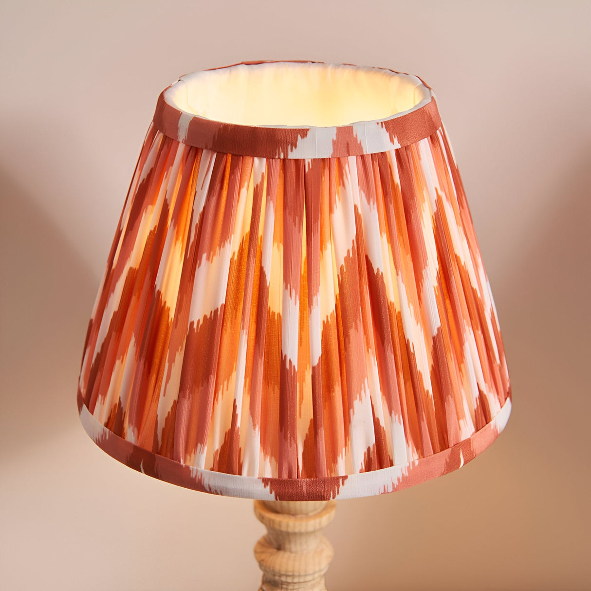 Endon Aldworth table lamp with a hand-pleated zigzag shade in orange, pink and white faux silk atop a turned natural wood spindle base.