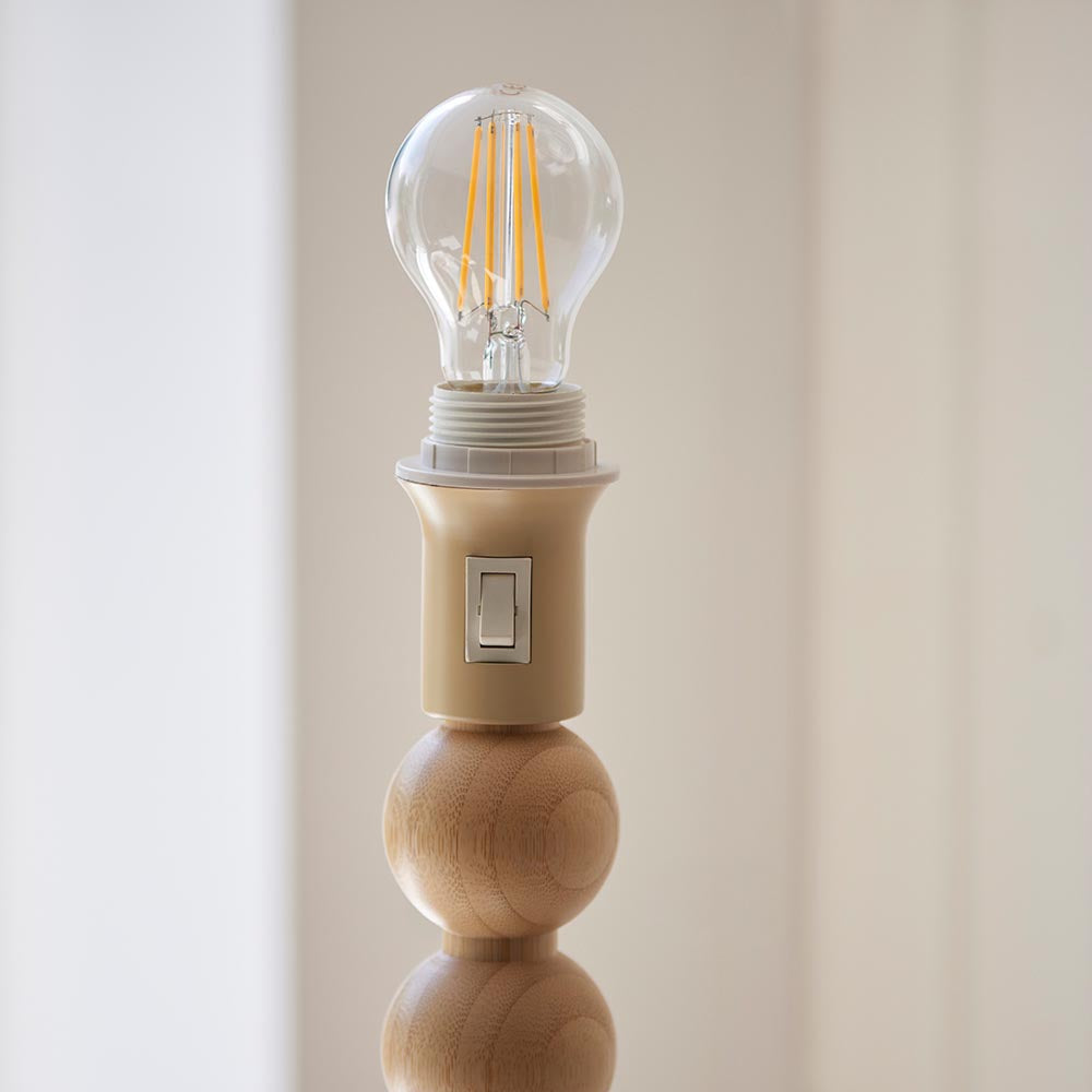 Close-up of the Endon Ashwood floor lamp's natural bamboo sphere base, cream E27 lamp holder with rocker switch, and clear filament bulb fitted.