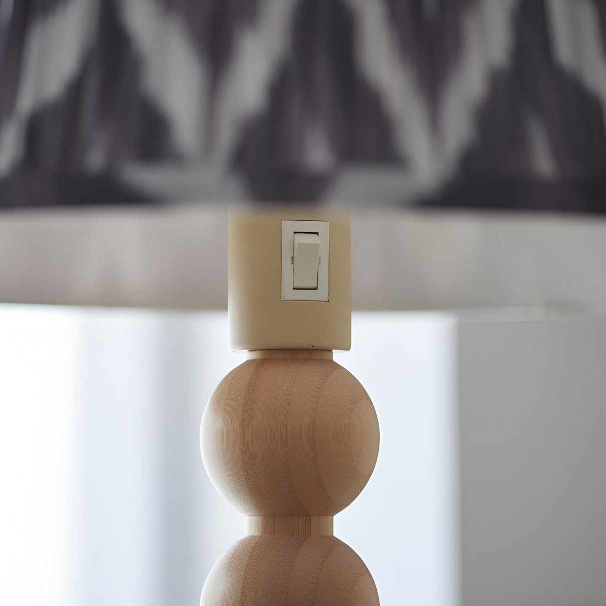 Ashwood Zigzag Floor Lamp in Grey, close-up of the on/off rocker switch atop a stacked bamboo sphere base beneath the tapered fabric shade.