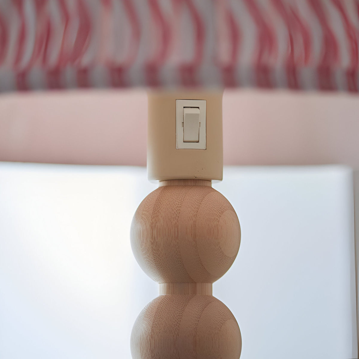 Close-up of the Endon Ashwood floor lamp showing the cream E27 lamp holder with rocker switch above stacked natural bamboo spheres and pink pleated shade.